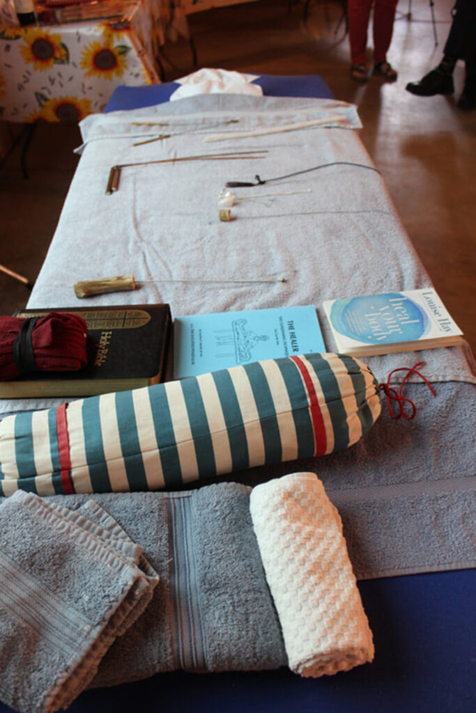 Geoffrey Morell massage table with tools and energy healing books seen from foot of table