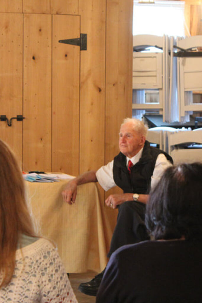 Geoffrey seated talking to students in barn