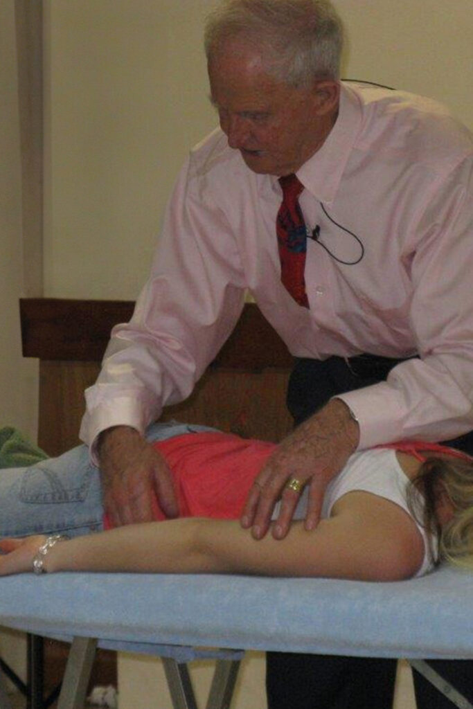 Geoffrey Morell demonstrating Clendenning Healing Technique on woman lying face down on massage table